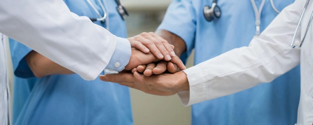 Healthcare workers with their hands placed together to show they are a team.